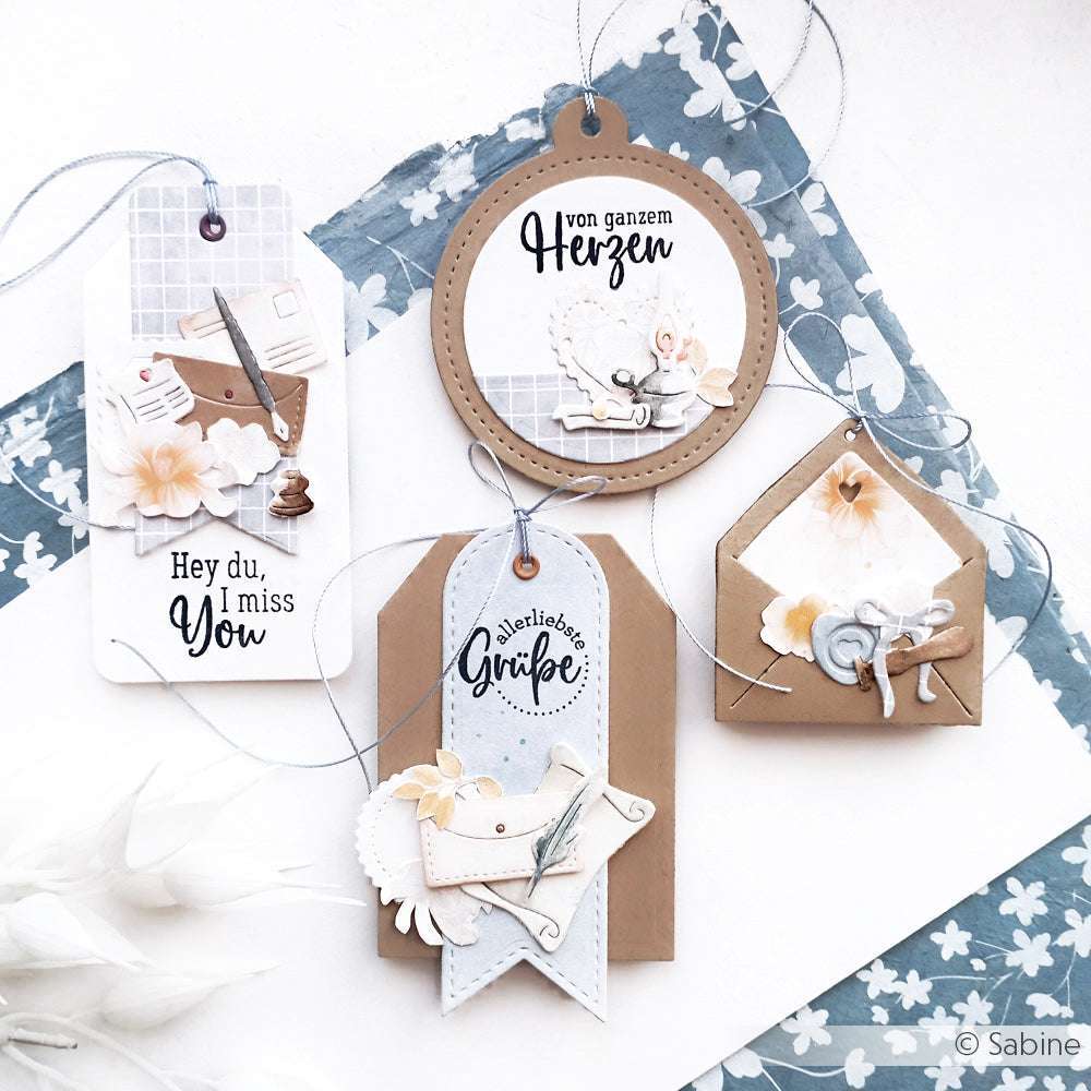 Vier handgefertigte Geschenkanhänger und Briefumschläge von Alexandra Renke mit Blumen- und Vintage-Motiven auf blauem und weißem Hintergrund, hergestellt mit hochwertigen Designpapieren für einen einzigartigen Touch.