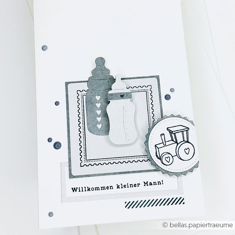 Handgefertigte Karte von Alexandra Renke mit Babyflasche, Rassel, Spielzeugeisenbahn und "Willkommen kleiner Mann!" auf Deutsch, hergestellt mit DieCut Systeme Akzente unter Verwendung von Motivstanze Fläschen Set und Stanzen für Designpapier.