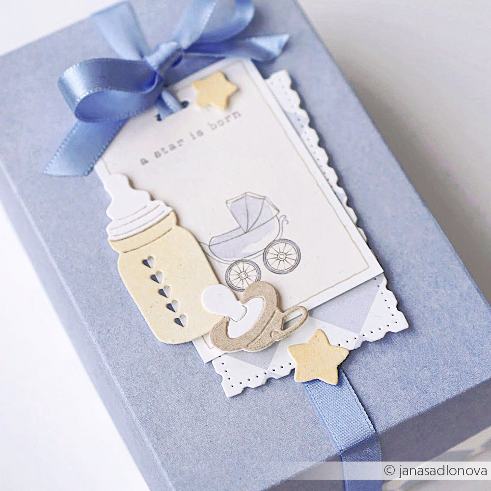 Blaue Geschenkschachtel mit Schleife, dekoriert mit Alexandra Renke Designpapieren und Babyausschnitten aus dem Motivstanze Fläschchen Set, veredelt mit einer "A star is born" Karte.