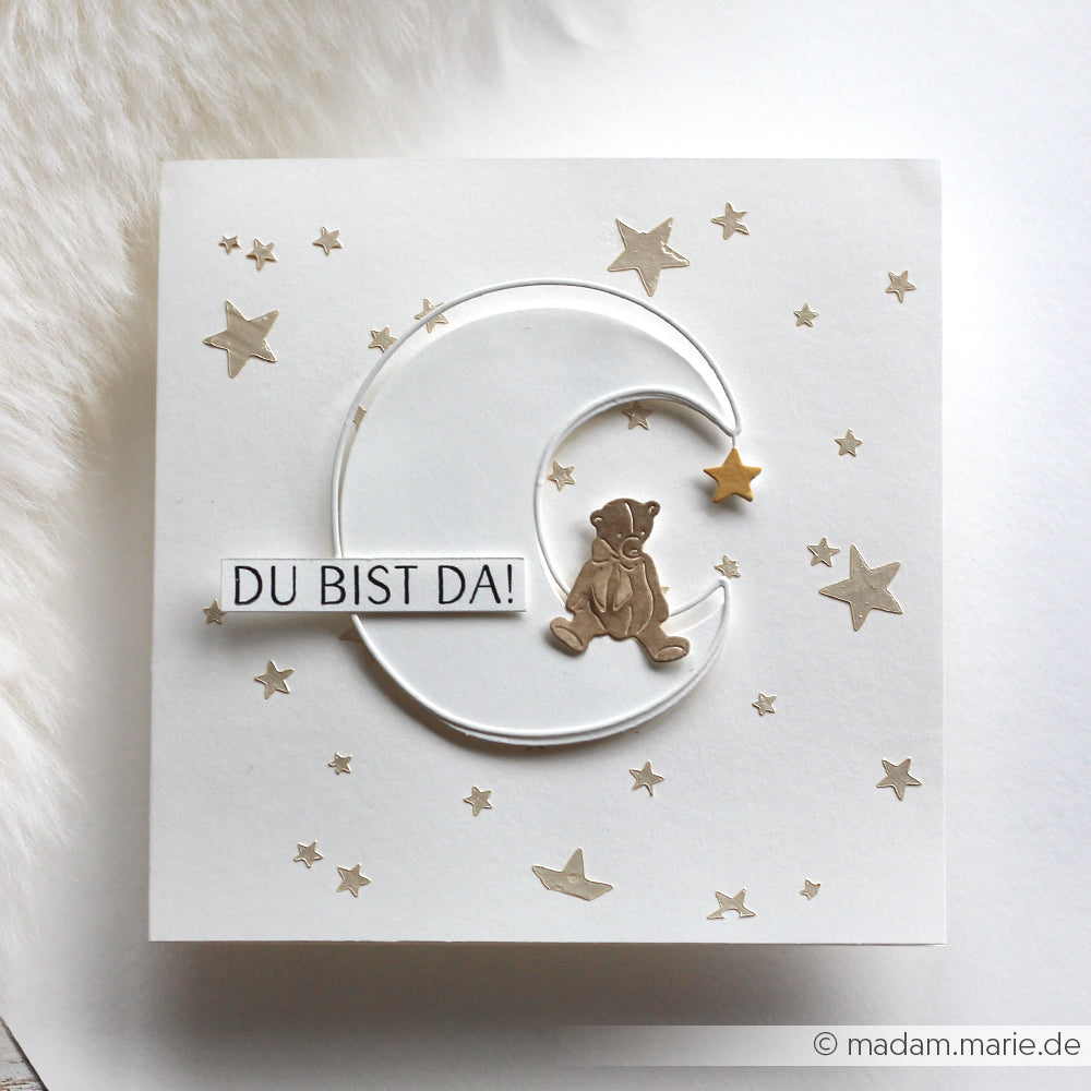 Alexandra Renke Grußkarte mit Teddybär auf Mondsichel, goldenen Sternen und "DU BIST DA!"-Text. Mit Motivstanze Outline Mond gestanztes Design - perfekt zu kombinieren mit Ihren Lieblingsdesignpapieren.