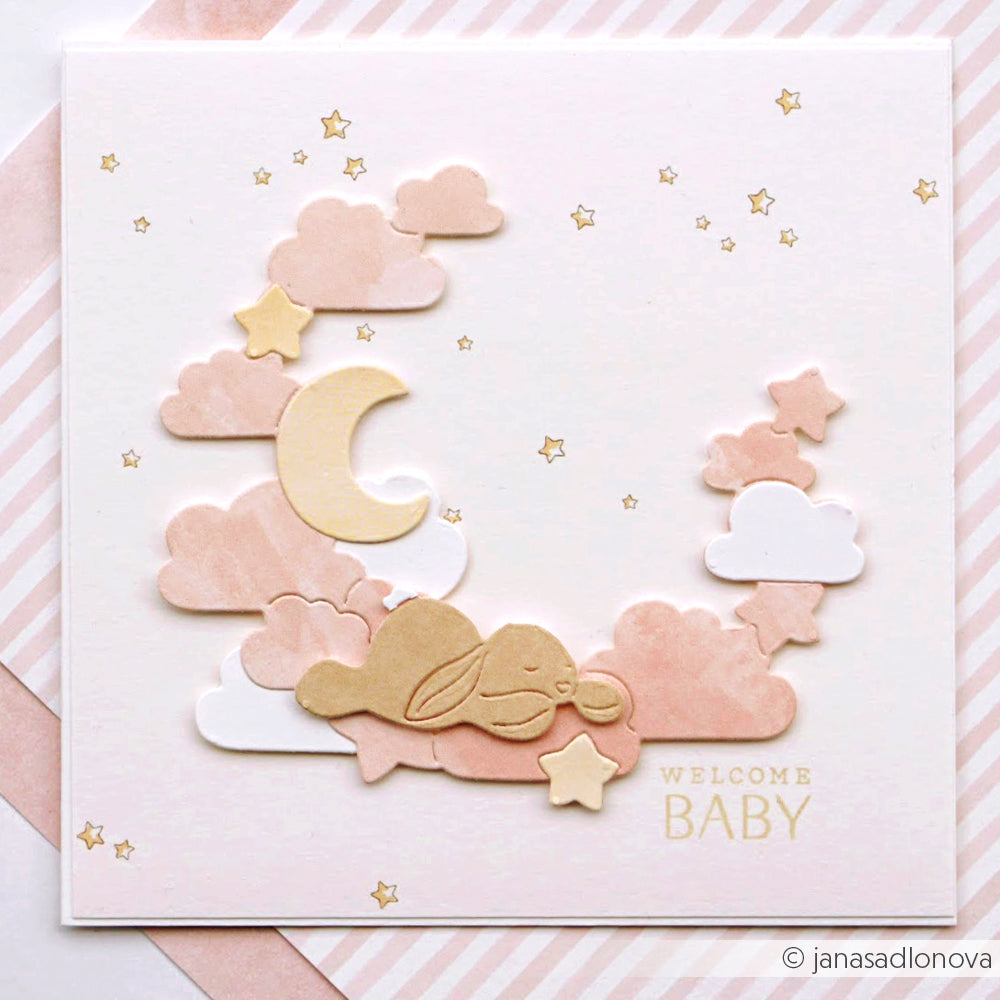 Pastellfarbene Babykarte von Alexandra Renke mit Wolken, Mondsichel, Sternen und einem schlafenden Häschen. Gestaltet mit Designpapieren. Text auf der Vorderseite: Willkommen Baby.
