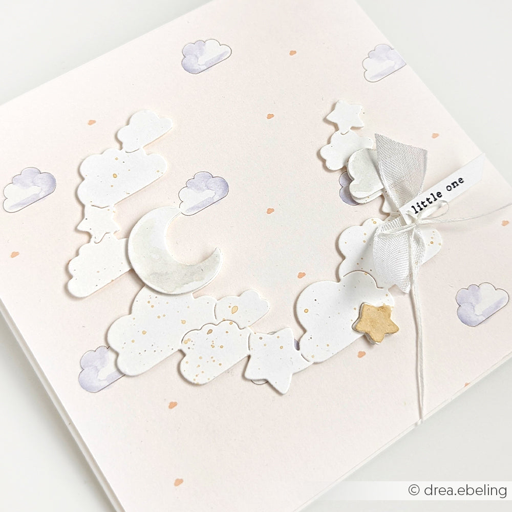 Eine pastellfarbene Karte mit Wolken, einer Mondsichel, einem goldenen Stern und einem weißen Band mit der Aufschrift "Kleines", gestaltet mit Alexandra Renke Designpapieren und Stanzformen für einen zauberhaften Touch.