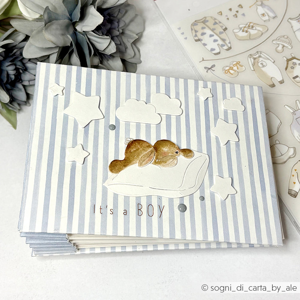Karte für einen kleinen Jungen mit einem Hasen auf einem Kissen mit Sternen und Wolken auf einem blau gestreiften Hintergrund - gestaltet mit der Alexandra Renke Motivstanze für präzise Formen und charmante Details.