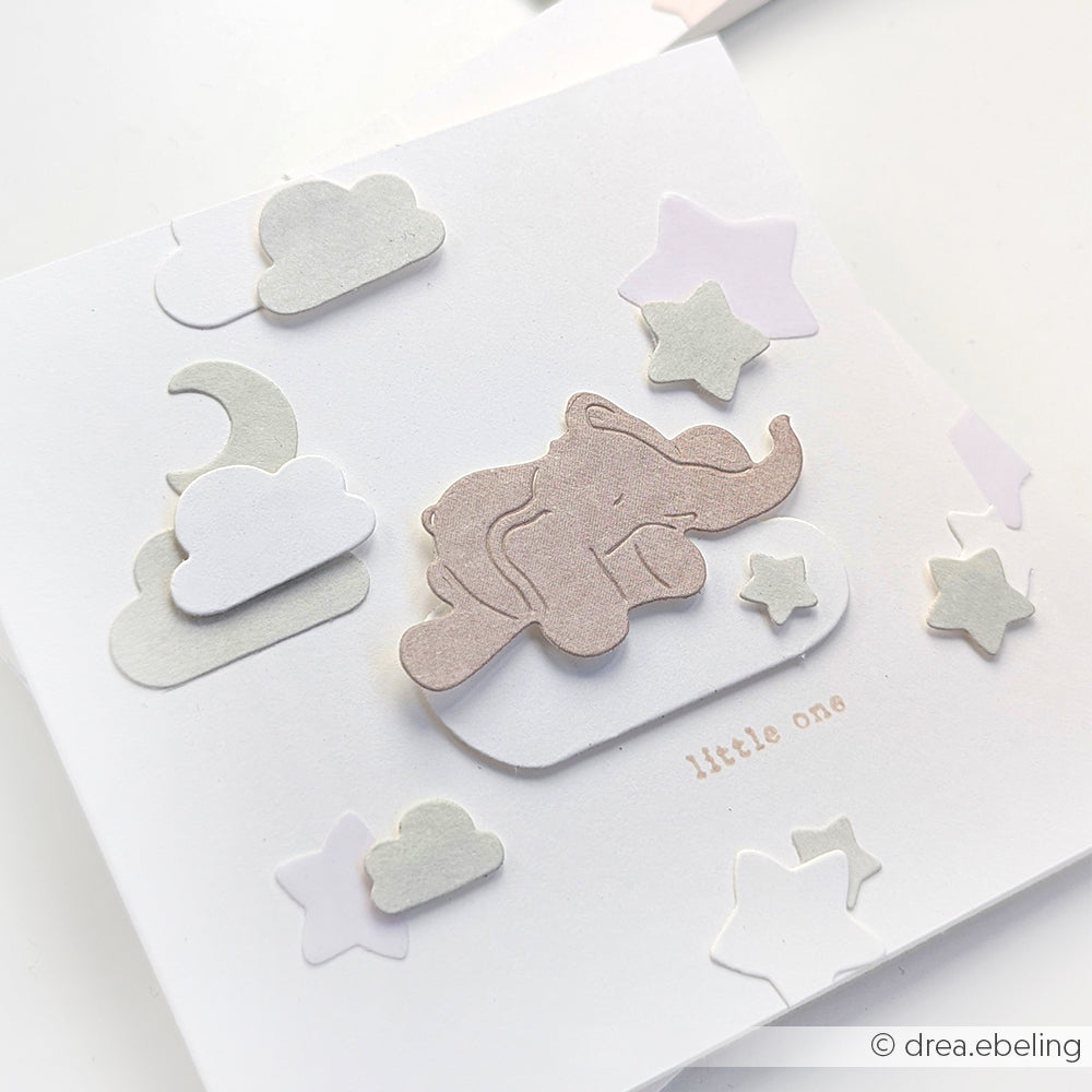 Eine pastellfarbene Karte von Alexandra Renke mit einem niedlichen Elefanten auf einer Wolke mit Sternen, Wolken und dem Text "little one", gestaltet mit Designpapieren und einer Motivstanze für zusätzlichen Charme.