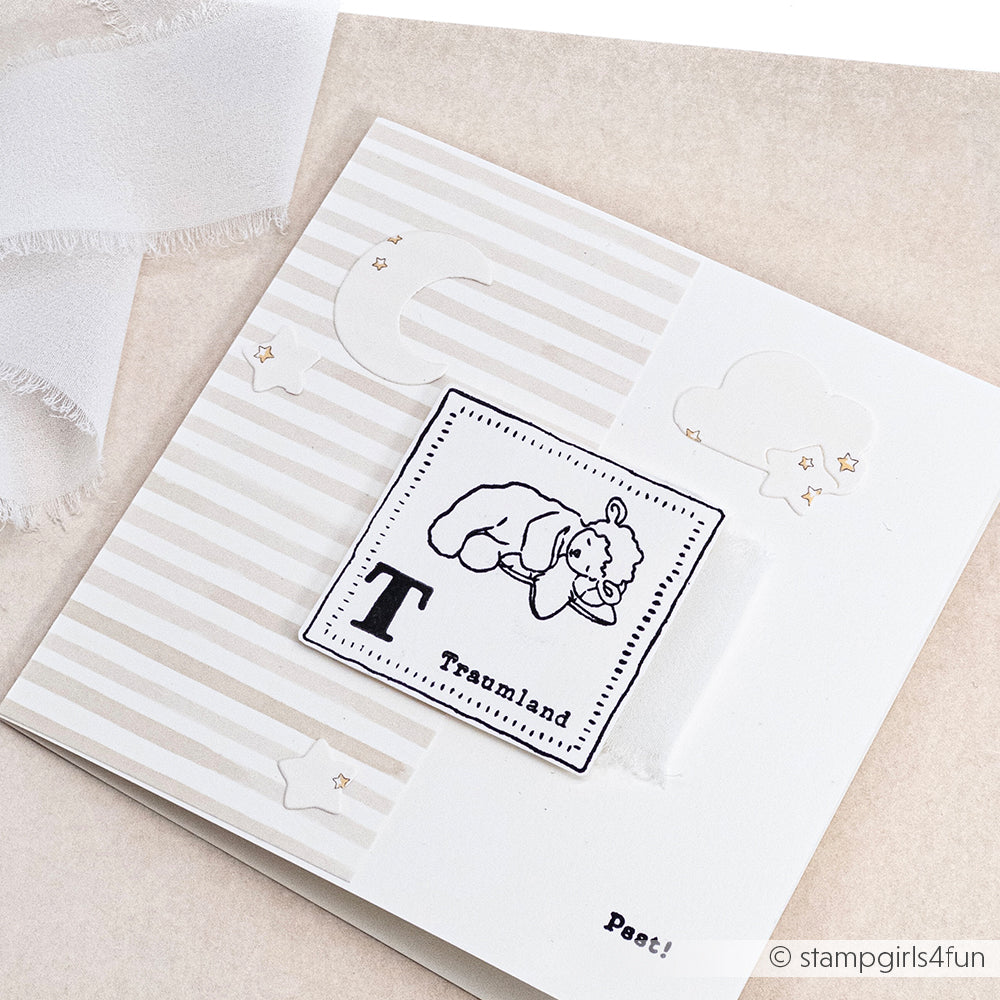 Handgemachte Karte von Alexandra Renke mit einem schlafenden Bären, Sternen, Mond, Wolken und dem Text "Traumland" auf einem neutralen gestreiften Hintergrund - gestaltet mit Designerpapier und detailliert mit DieCut Systemen.