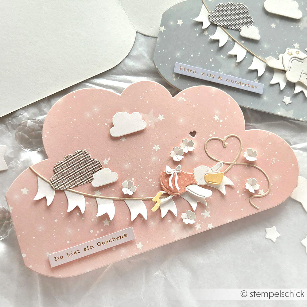 Rosafarbene Wolkenkarte von Alexandra Renke mit einem Vogel, Herzen, Spruchbändern und deutschem Text, hergestellt aus Designpapier und verziert mit Wolken und Sternen.