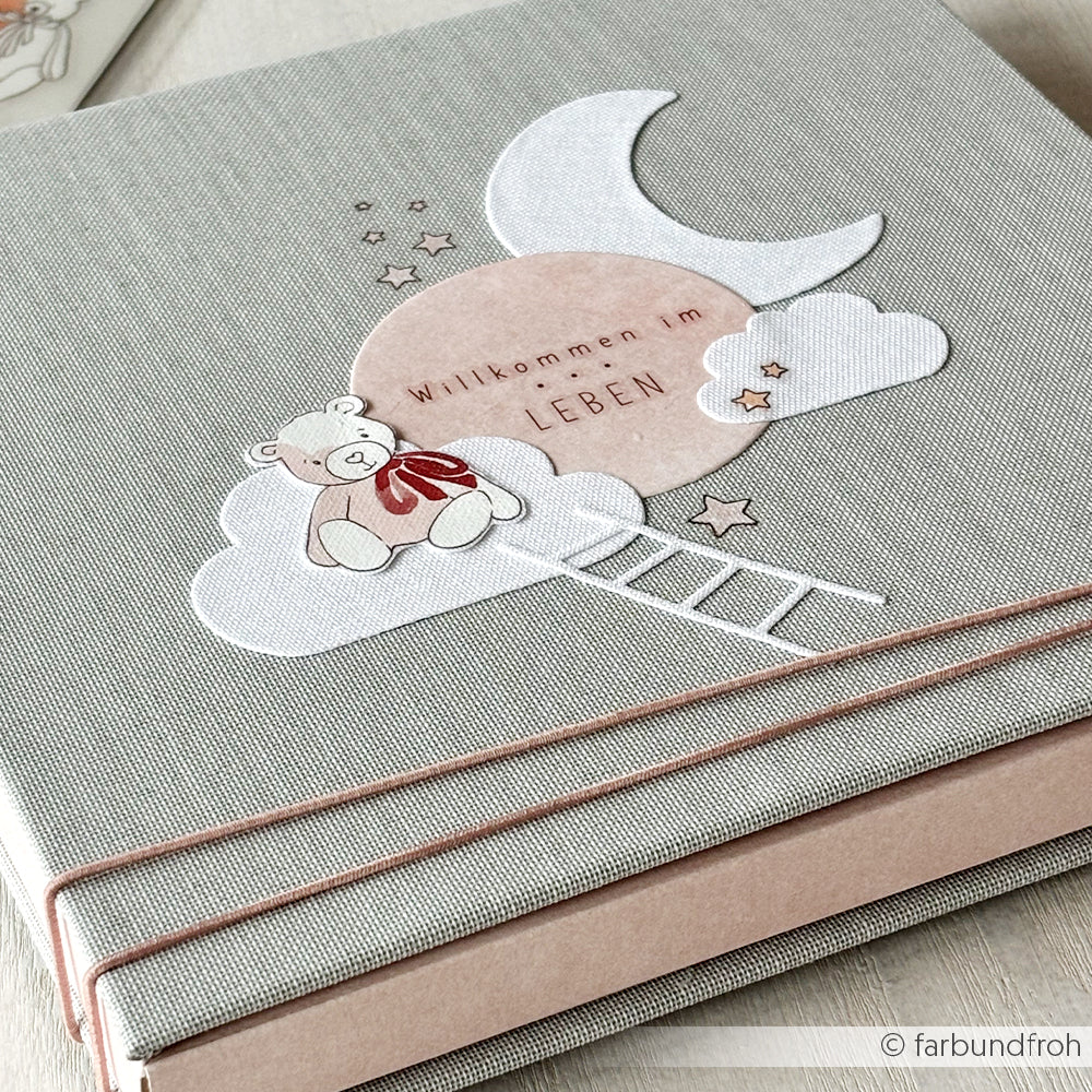 Ein Babyalbum-Cover von Alexandra Renke mit Designpapieren, das einen Teddybären, Wolken, eine Leiter, den Mond und den Text "Willkommen im Leben" zeigt.