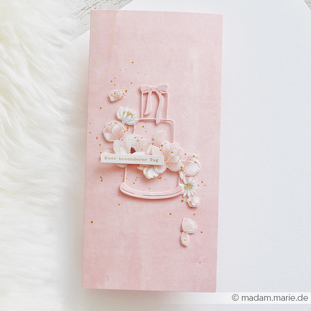 Eine rosa Karte von Alexandra Renke mit einer Torte im 3D-Umriss, mehrschichtigen Blumen und einem Anhänger mit der Aufschrift „Euer besonderer Tag“, die mit filigranen Stanzformen für elegante Details gestaltet wurde.