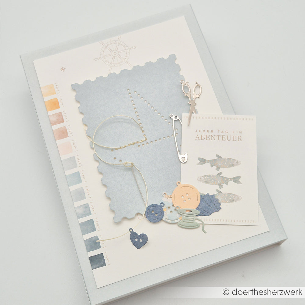 Eine handgefertigte Karte im maritimen Stil von Alexandra Renke mit Fischen, Knöpfen, Scheren, Farbmuster und Designpapieren – ideal für die Verwendung mit Ihren bevorzugten Stanzsystemen oder der Motivstanze „Postkarte“!.