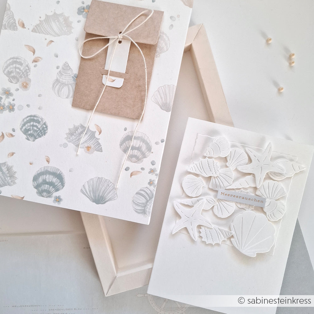 Zwei handgefertigte Karten mit Muschel- und Seesternmotiven in sanften, neutralen Farbtönen, gestaltet mit der Motivstanze „Kleines Muschel-Set“ von Alexandra Renke. Eine der Karten wird zusammen mit einem verschnürten Umschlag geliefert, was diesem bezaubernden Set eine elegante Note verleiht.