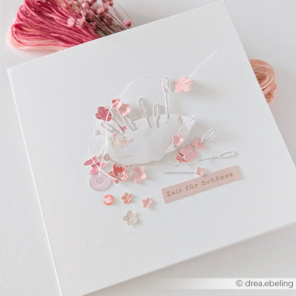 Eine weiße Karte von Alexandra Renke zeigt einen 3D-Regenschirm, rosa Blumen, Knöpfe und den deutschen Schriftzug „Zeit für Schönes“, gestaltet mit eleganten Designpapieren.