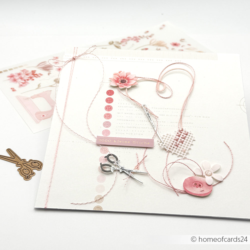 Handgefertigte Karte mit rosa Verzierungen, Garn, Schere und Knöpfen, deren Details mit den „Motivstanze Handarbeits-Anhänger“-Stanzformen von Alexandra Renke auf weißem Hintergrund gestaltet wurden.