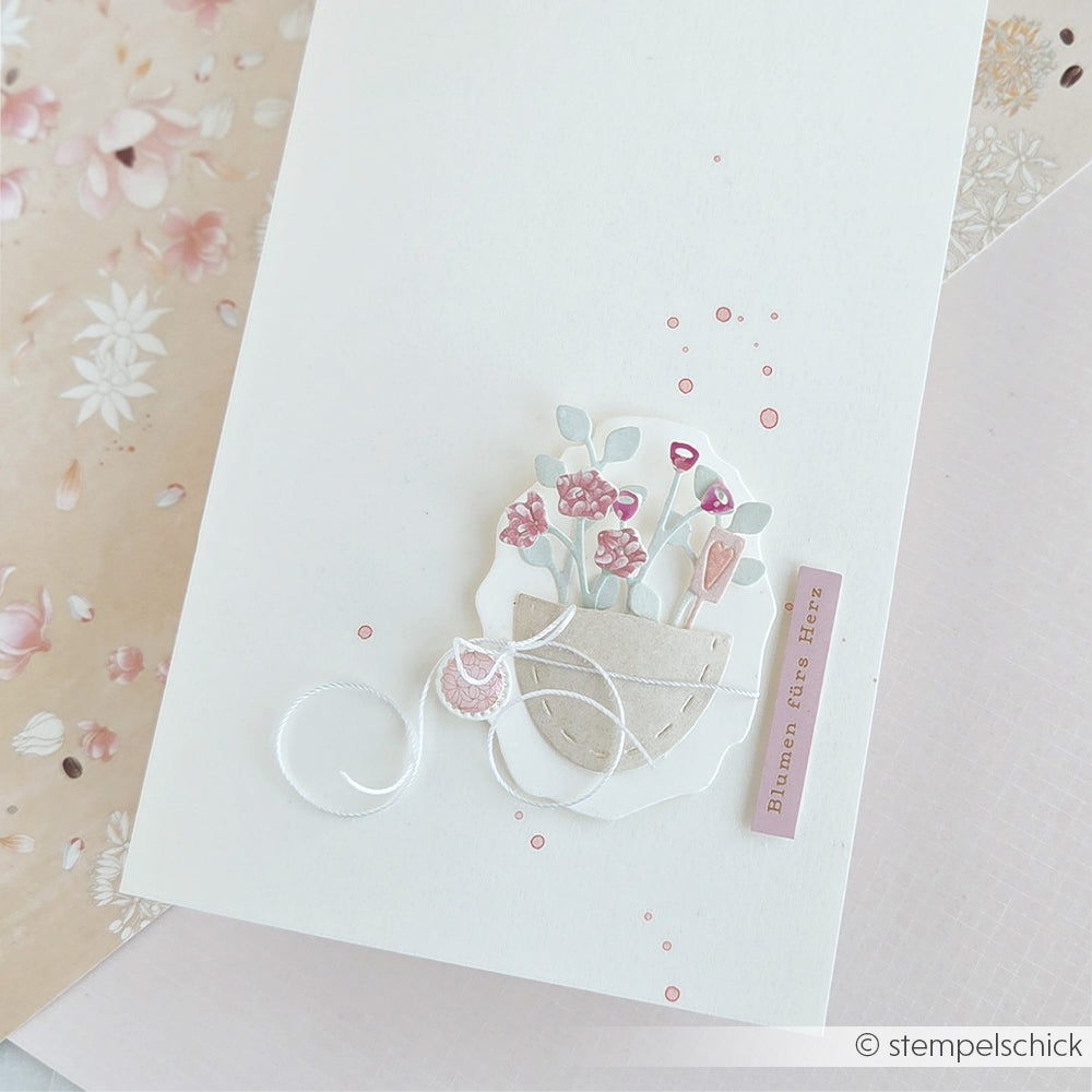 Handgefertigte Karte von Alexandra Renke mit einem pastellfarbenen Blumentopf, rosa Blumen und einem Anhänger mit der Aufschrift „Blumen fürs Herz“, gestaltet aus edlem Designpapier und mit der Motivstanze „Stickrahmen Oval“ für den besonderen Charme.