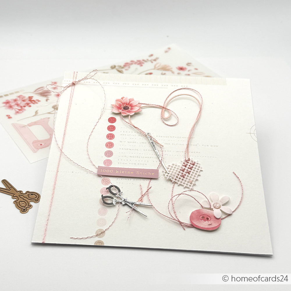 Eine handgefertigte Karte von Alexandra Renke mit rosa Garn, Knöpfen, einer Blume und Scherenverzierungen auf weißem Hintergrund, gestaltet mit Designpapieren und der Motivstanze „Stickrahmen Rund“ von DieCut Systeme für einzigartige Details.