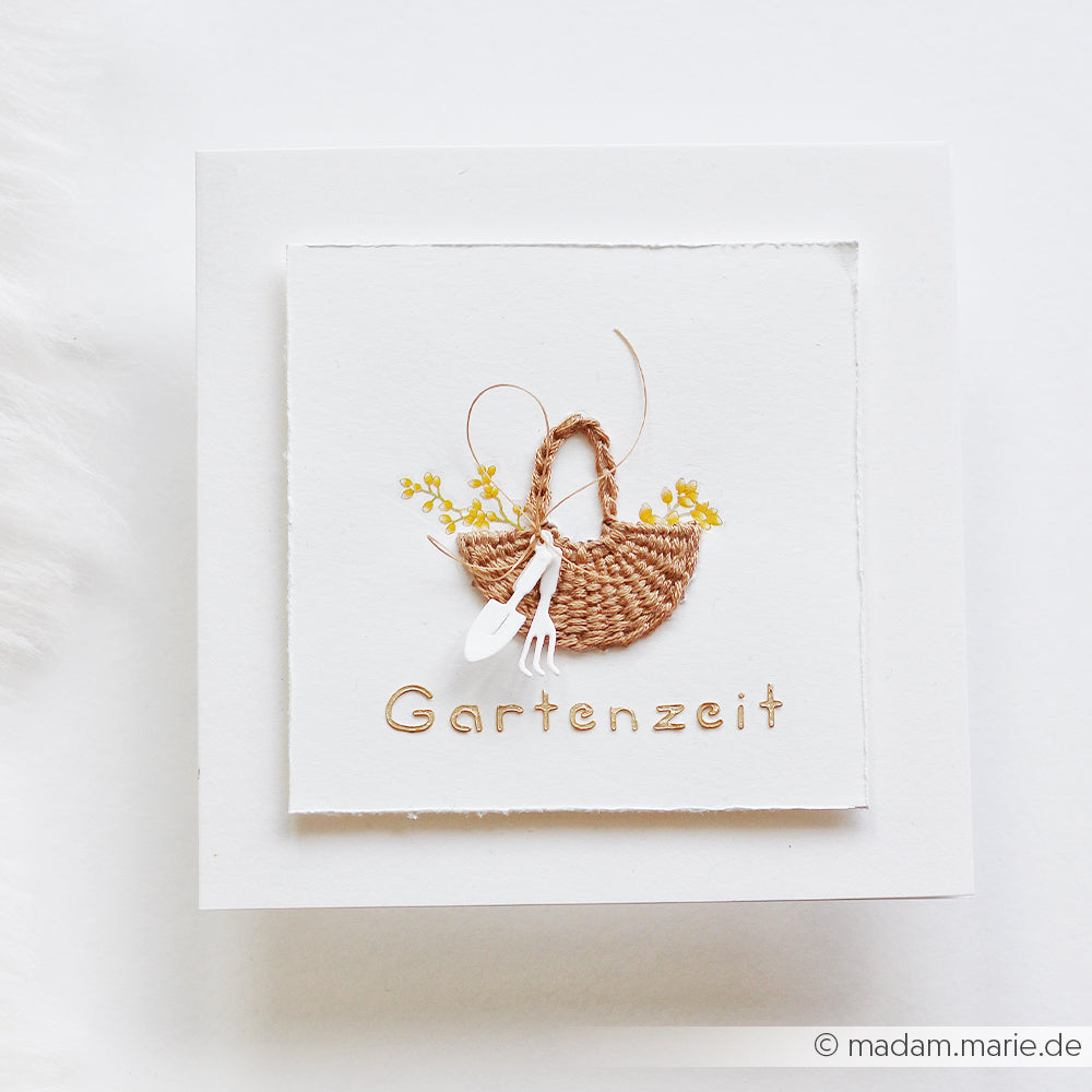 Bestickter Gartenkorb mit Gartengeräten und Blumen, verziert mit dem Motivstanze-Anhänger „Gartenspaß“ über der Aufschrift „Gartenzeit“. Eine perfekte Wahl für Fans von Alexandra Renke, die DieCut-Systeme und Stanzen für Designpapiere lieben.