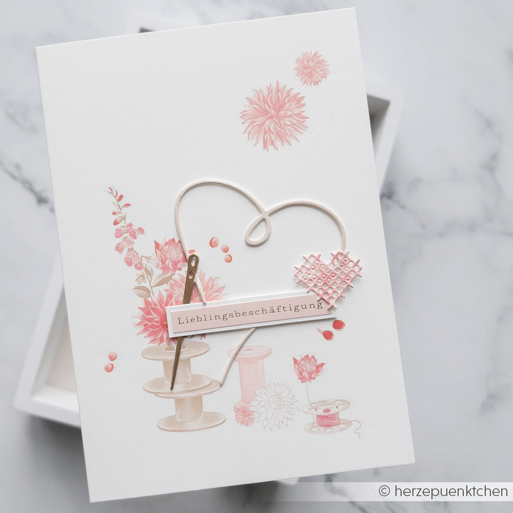 Weiße Karte von Alexandra Renke mit rosa Blumenmotiven, einem Herzumriss und der Aufschrift „Lieblingsbeschäftigung“ auf Deutsch – ideal zum Basteln mit Designpapieren oder zum Kombinieren mit Ihrer Lieblings-Motivstanze.