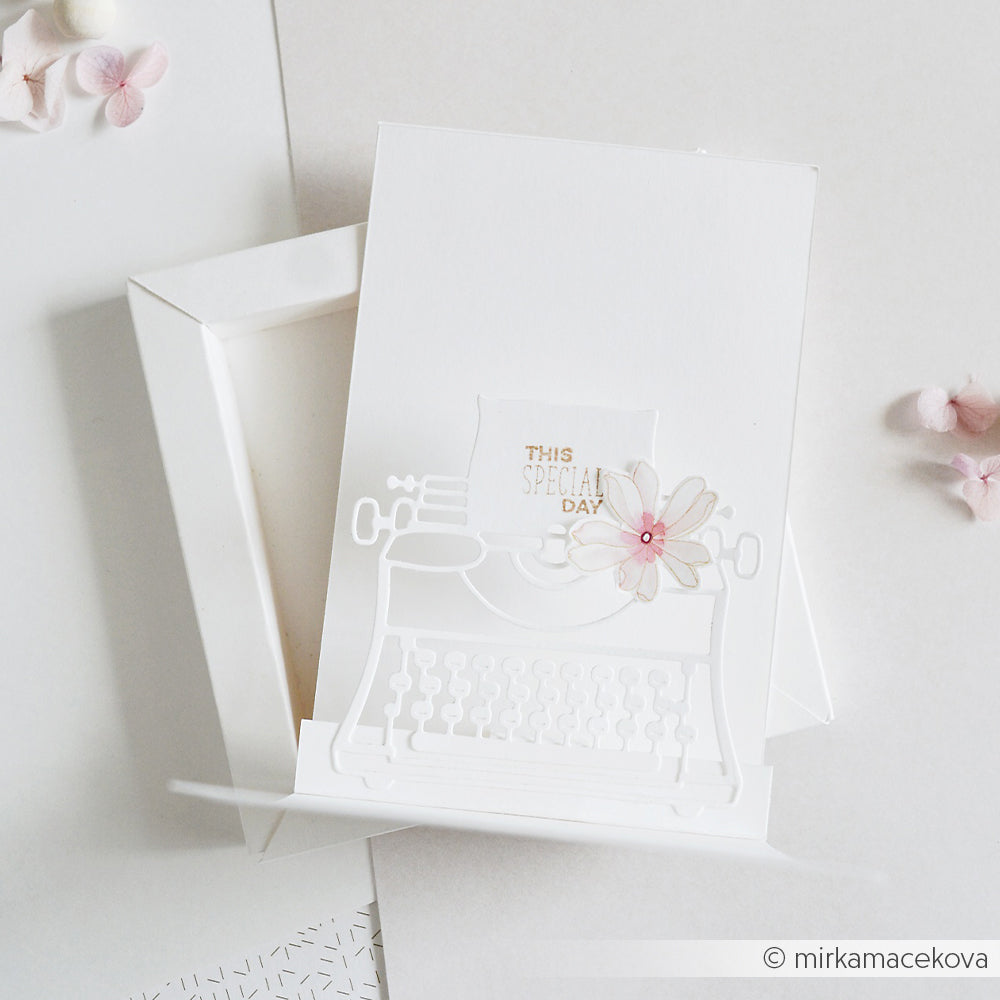 Weiße Karte von Alexandra Renke mit einem zarten, ausgestanzten „Schreibmaschine Outline“-Motiv und einer rosa Blume sowie der Aufschrift „This Special Day“ auf einem weißen Kästchen. Ideal für die Verwendung mit verschiedenen Stanzsystemen, um elegante und individuelle Grußkarten zu gestalten.