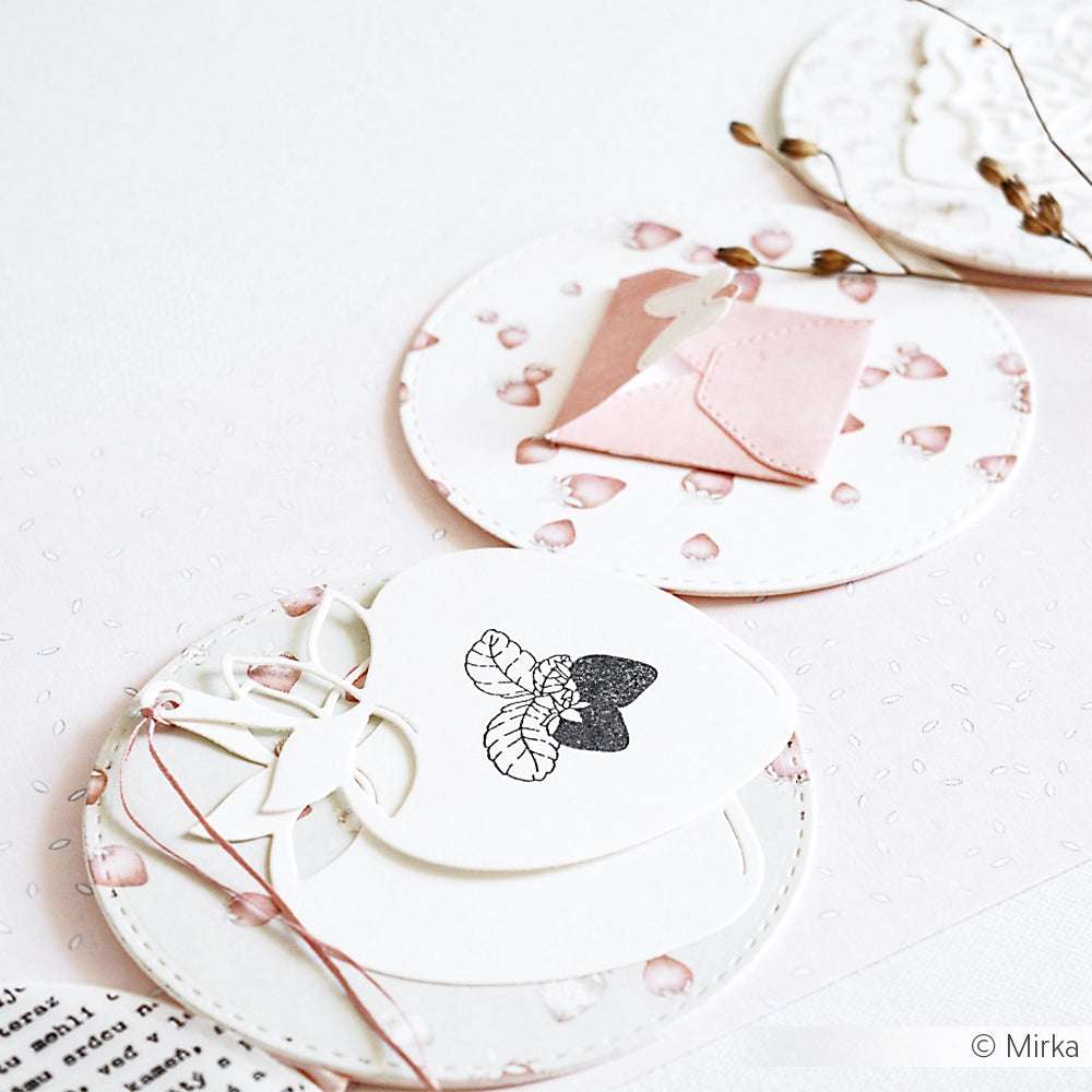 Drei dekorative runde Karten von Alexandra Renke mit floralen Motiven auf Designpapieren, mit einem kleinen rosafarbenen Umschlag, alles auf einer weißen Fläche angeordnet.