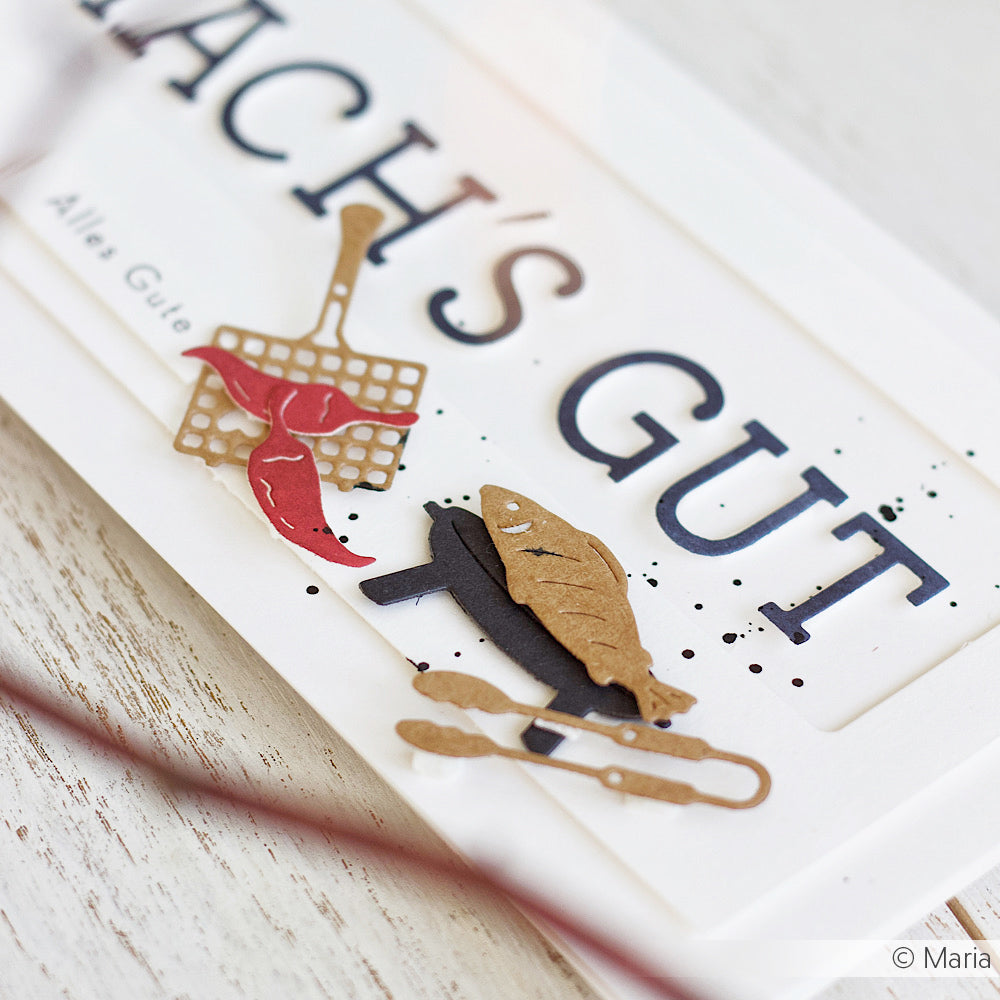Handgemachte Karte mit Papierausschnitten, die mit den Stanzformen des Mini-Grill-Sets von Alexandra Renke hergestellt wurden, darunter ein Fisch, ein Grill, ein Pfannenwender und der Schriftzug "ALLES GUT".