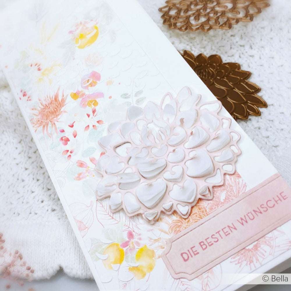Eine Blumenkarte mit Alexandra Renke Dies und einer weißen Schichtblume, die mit der Motivstanze Dahlienblüte hergestellt wurde, zeigt DIE BESTEN WÜNSCHE auf einem pastellfarbenen Hintergrund.