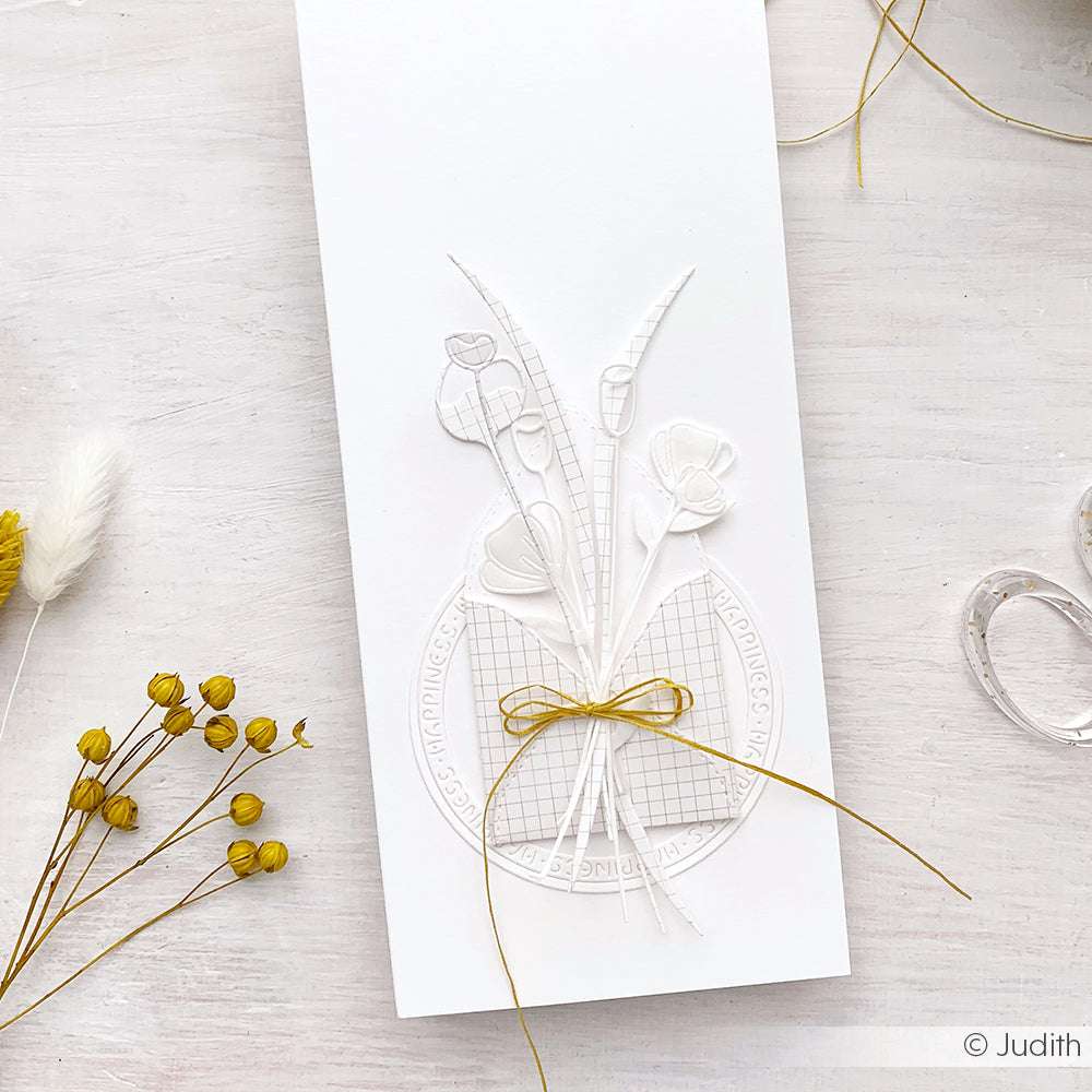 Weiße Prägekarte von Alexandra Renke mit einem zarten Artistblumen-Blumenmotiv und einer goldenen Schleife - ideal für kreative Ideen mit Motivstanze und Stanzsystemen.