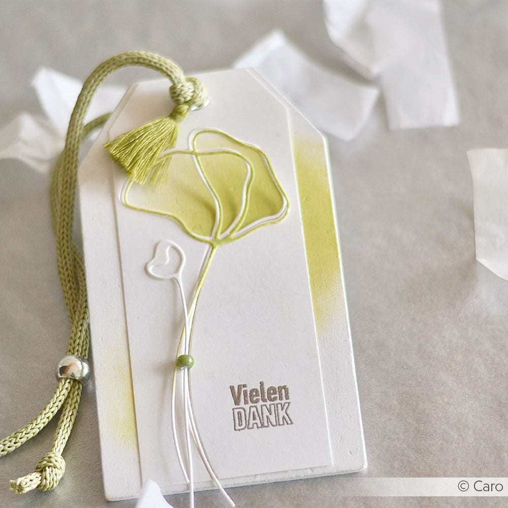 Weißer, handgefertigter Dankesanhänger von Alexandra Renke, mit grüner Kordel, Quaste, Drahtblume aus der Motivstanze und dem Text "Vielen DANK".