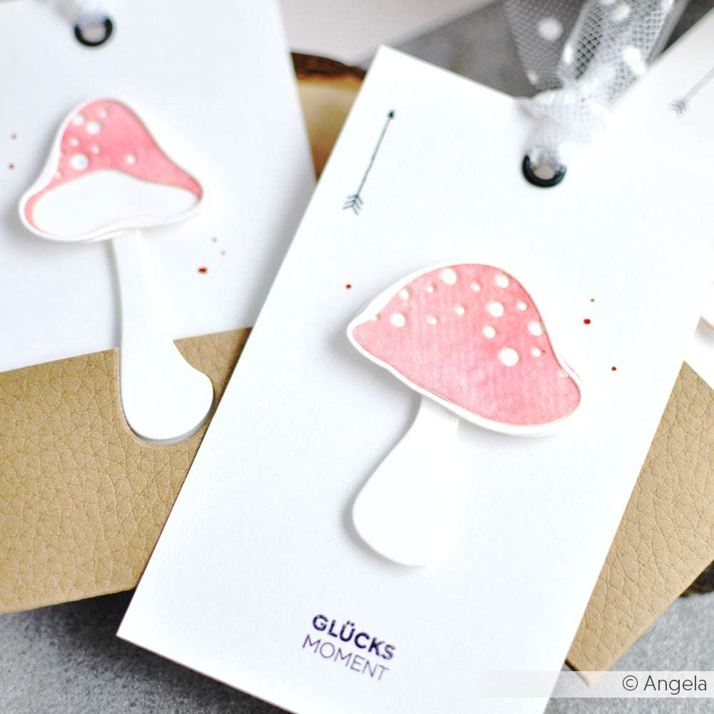Eine handgefertigte Karte von Alexandra Renke mit der rosa-weißen Pilz-Illustration von Artist Pilz 2 und dem Schriftzug "GLÜCKS MOMENT" am unteren Rand, hergestellt mit der Motivstanze für charmante Details.
