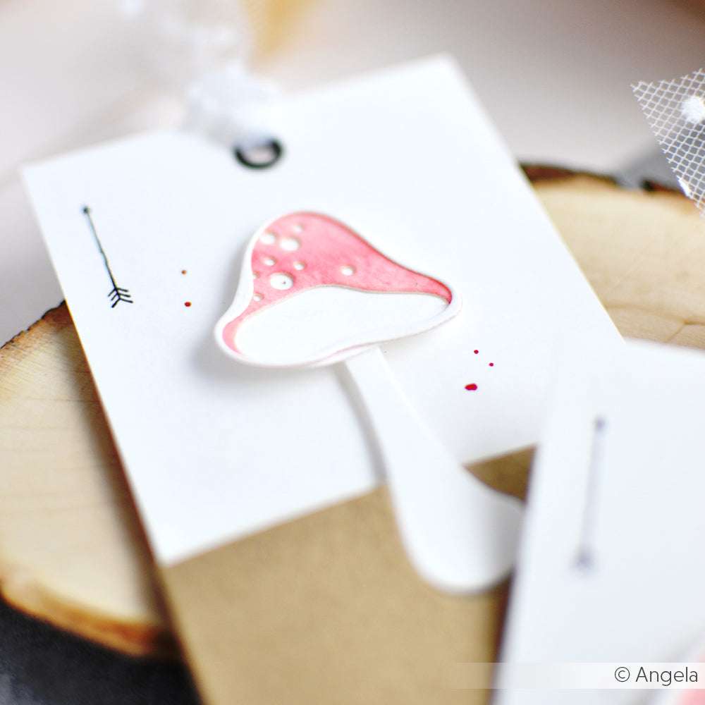 Eine handgefertigte Karte mit einem rosa-weißen Pilzmotiv, hergestellt mit der Alexandra Renke Motivstanze Artist Pilz 5, platziert auf einer Holzunterlage.