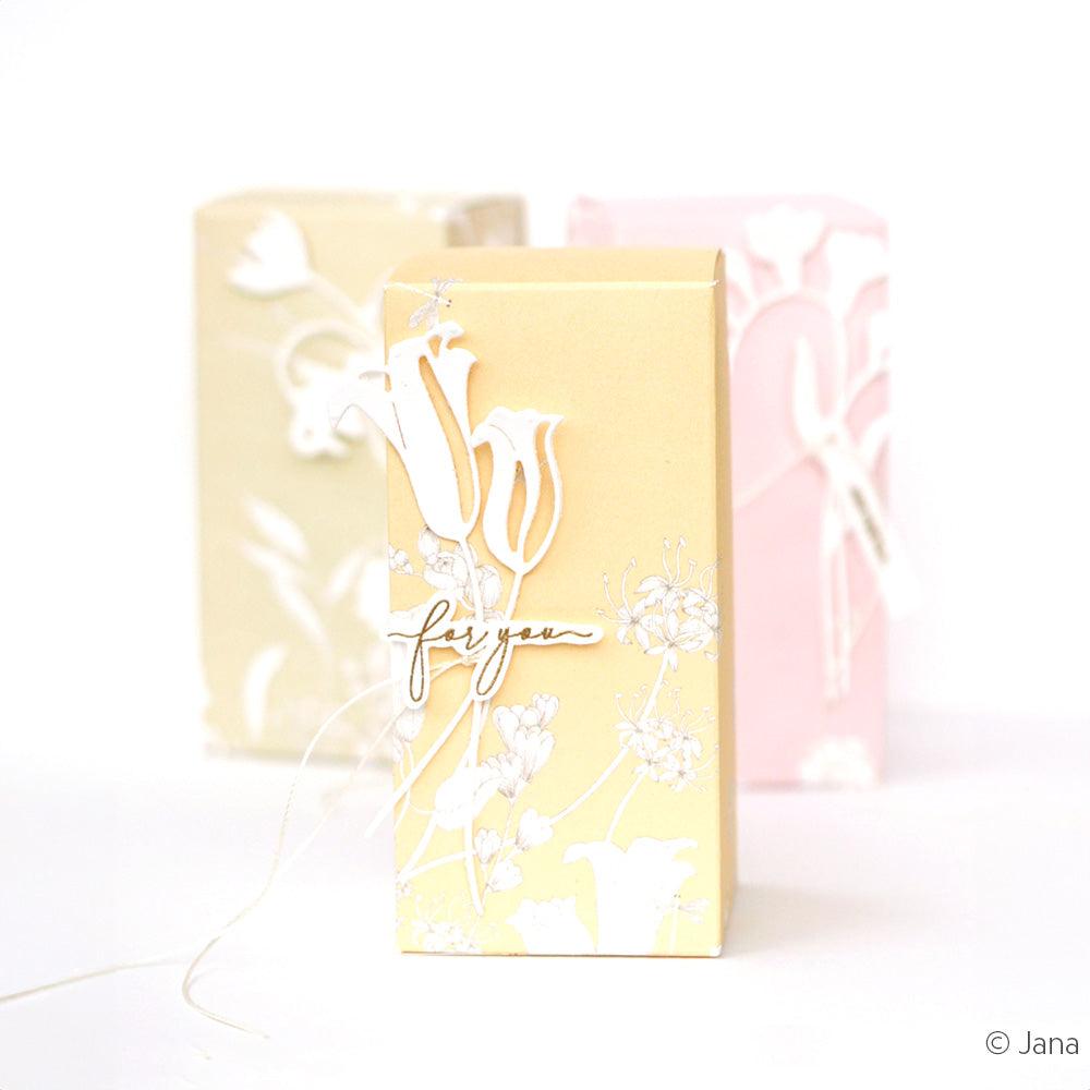 Drei pastellfarbene, florale Geschenkboxen, die mit Alexandra Renke Stanzsysteme Dies hergestellt wurden, wie die Motivstanze Große Kelchblüten. Auf der Vorderseite der gelben Schachtel steht "for you" und sie ist mit zarten weißen Blumen verziert.