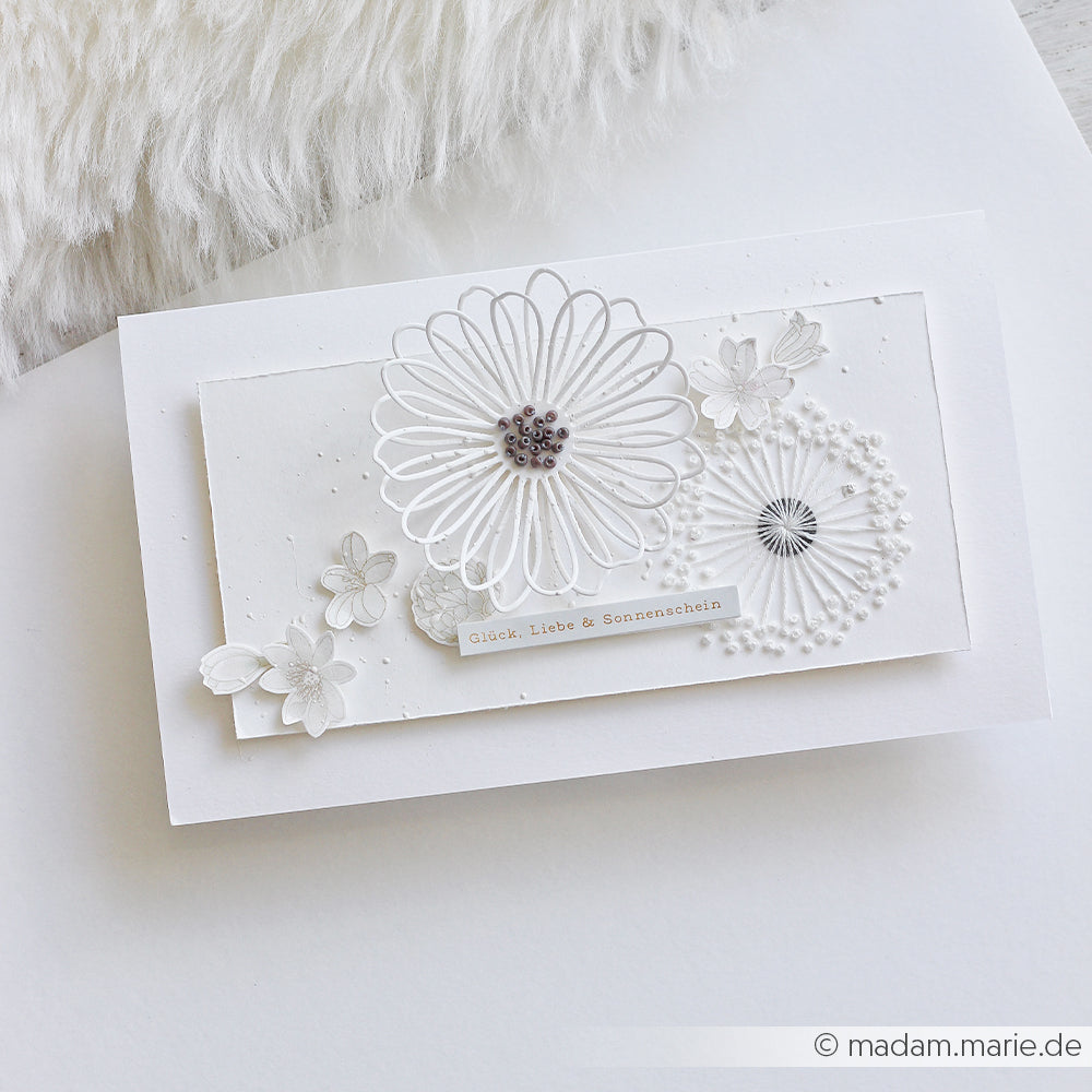 Weiße Grußkarte von Alexandra Renke, gestaltet mit Designpapieren und geprägten Blumenmotiven, die mit der Motivstanze „Margerite Outline“ ausgestanzt wurden, mit den Aufschriften „Glück“, „Liebe“ und „Sonnenschein“.