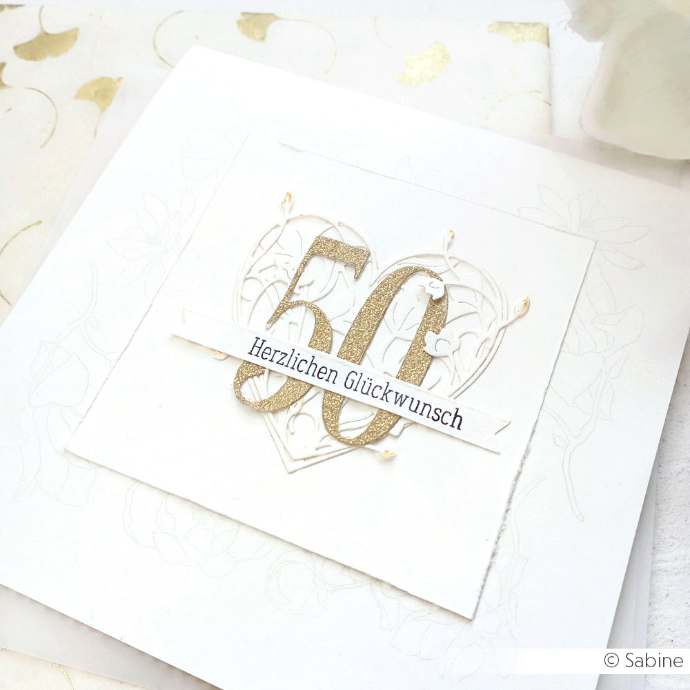 Elegante weiße Karte von Alexandra Renke mit einer goldenen 50 und "Herzlichen Glückwunsch" über einem Herzmotiv, hergestellt mit hochwertigen Designpapieren und der Motivstanze Florales Herz - perfekt für besondere Anlässe.