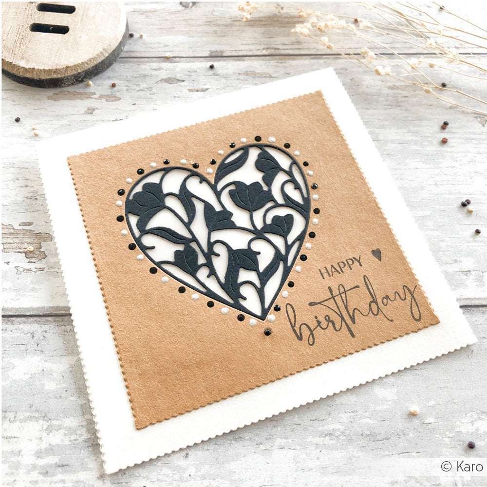 Quadratische Geburtstagskarte von Alexandra Renke mit ausgestanztem Blumenherz (Motivstanze Blumenherz) und Text "Happy Birthday" auf braunem Papier.