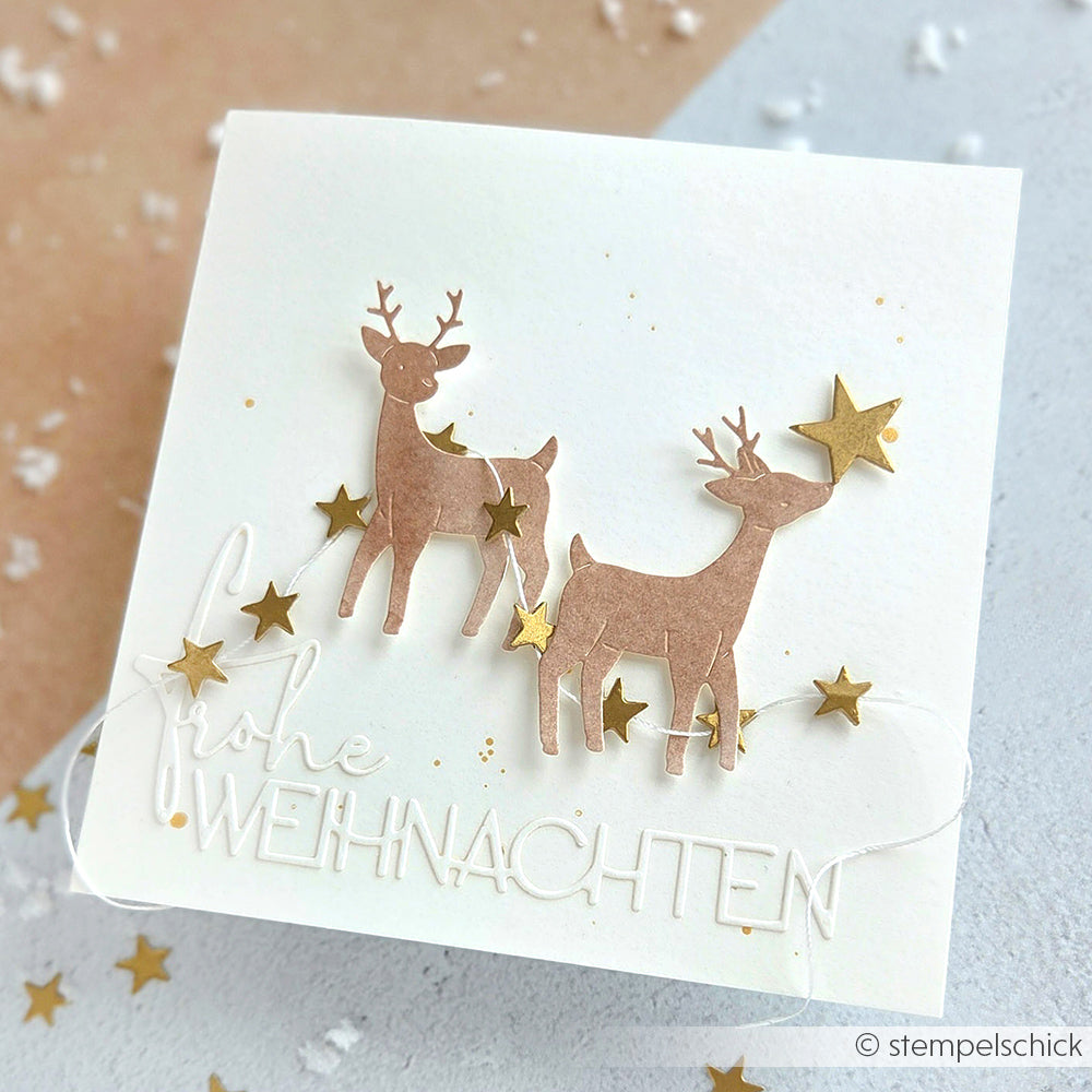 Die weiße Weihnachtskarte von Alexandra Renke mit zwei Rentieren, goldenen Sternen und dem erhabenen Text "Frohe Weihnachten" wurde mit der Motivstanze Tierische Sternfreunde und hochwertigen Stanzsystemen für einen festlichen Look gestaltet.