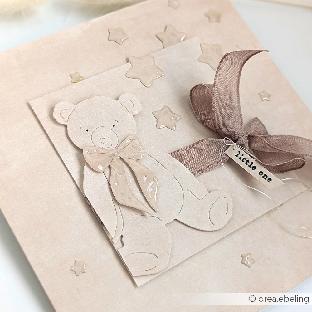 Handgefertigte beigefarbene Karte mit Teddybär aus Papier, Schleife, Sternchen und einem "Little One"-Anhänger - hergestellt mit hochwertigen Alexandra Renke Designpapieren für ein charmantes Finish.
