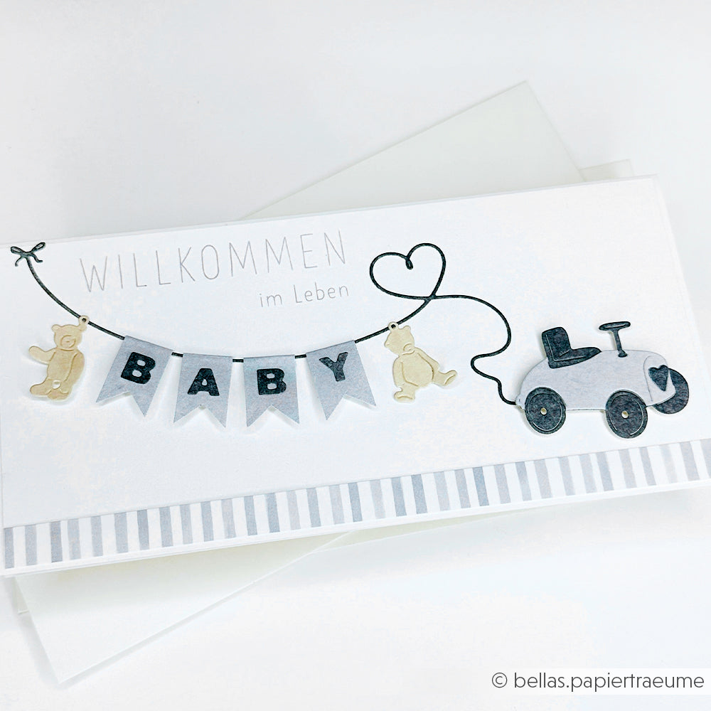Die weiße Karte von Alexandra Renke zeigt "Willkommen im Leben", BABY Wimpel, Teddybären, Herzen und ein Spielzeugauto - perfekt für DieCut Systeme oder mit der Motivstanze Kleine Bärchen Anhänger.