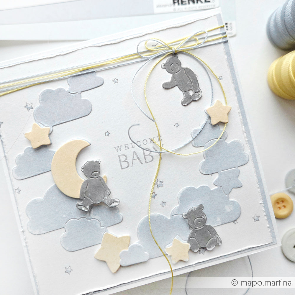 Handgemachte Karte von Alexandra Renke mit Teddybären, Wolken, Sternen, einem Mond und dem Text "Welcome Baby", gebunden mit einer gelben Schleife. Erstellt mit den Stanzsystemen Stanzformen wie der Motivstanze Kleine Bärchen Anhänger für bezaubernde Details.