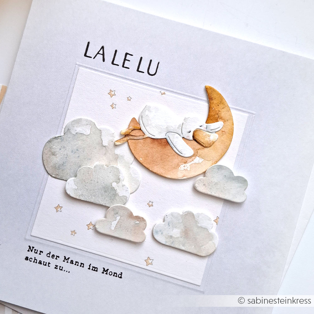 Verträumte Illustration von Alexandra Renke: Ein Kaninchen schläft auf einer Mondsichel mit Wolken und Sternen, "LA LE LU" oben - perfekt für Stanzsysteme oder als niedliches Motiv wie die Motivstanze Gute-Nacht-Ente.