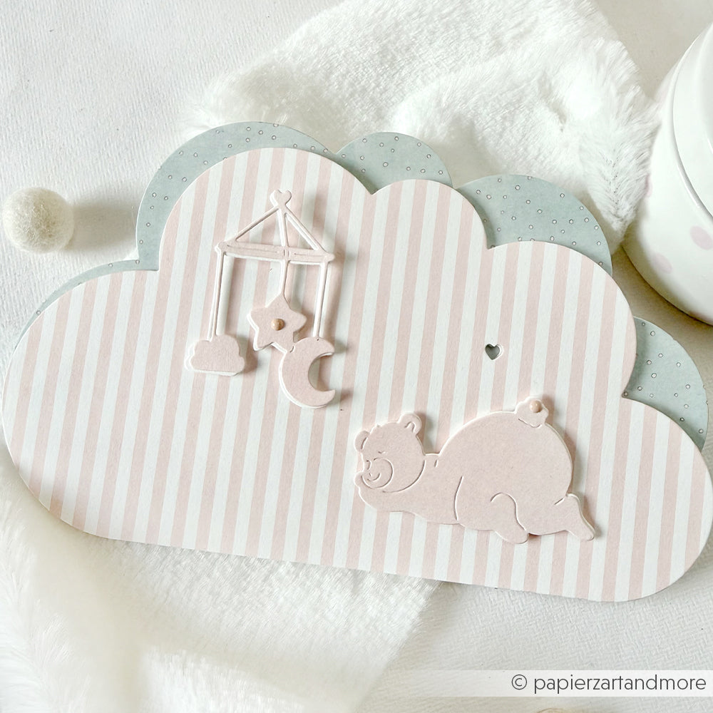 Wolkenförmige Karte von Alexandra Renke aus weichem Designpapier mit pastellfarbenen Streifen, einem Mobile und einem verspielten Bären auf weißem Hintergrund - ideal, um Ihre Lieblingskreationen von Motivstanze zu präsentieren.