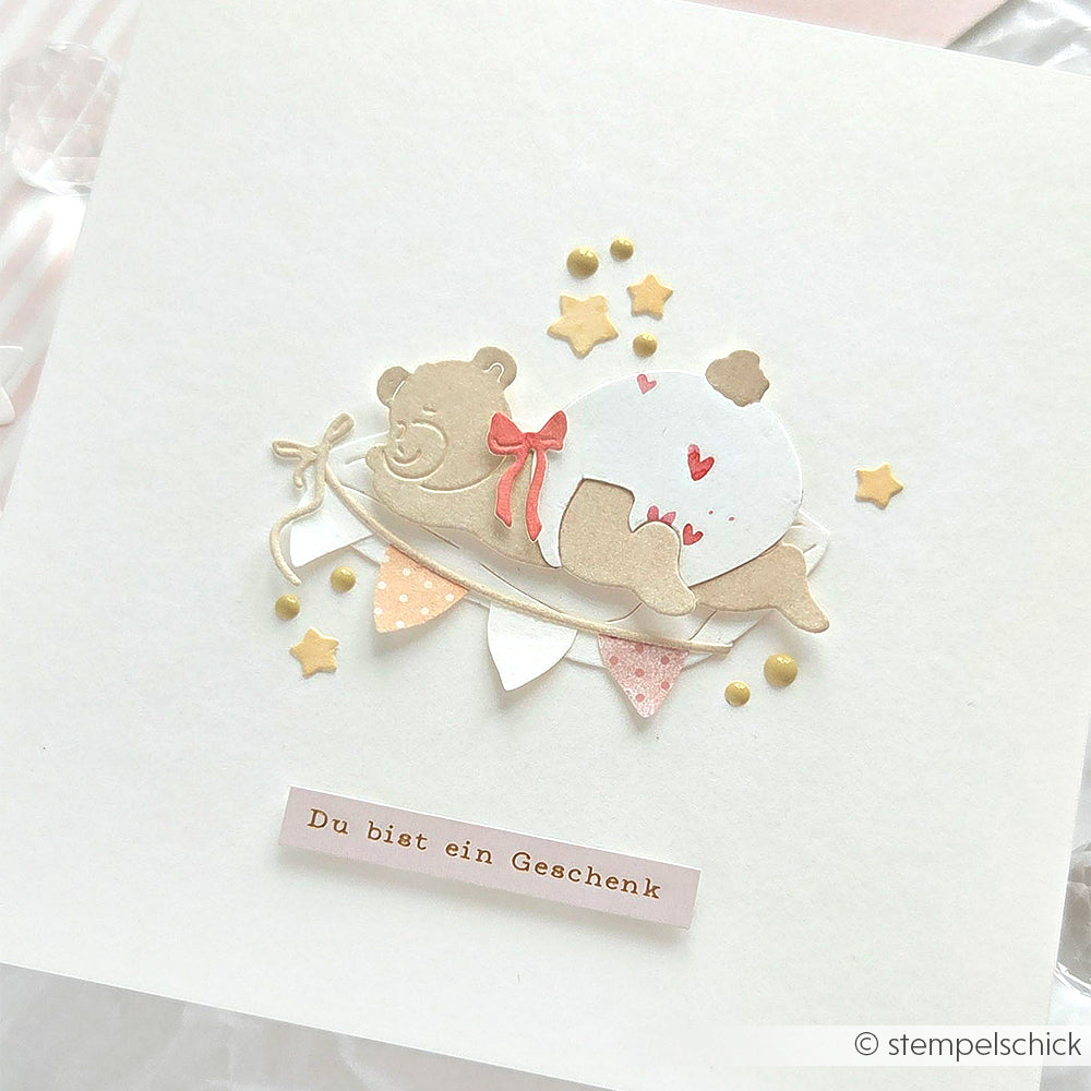 Handgemachte Karte von Alexandra Renke mit Designpapieren und DieCut Systemen, mit einem süßen Bären in einer Windel auf einer Wolke, Sternen, Bannern und "Du bist ein Geschenk" mit Motivstanze Schlafgefährten.