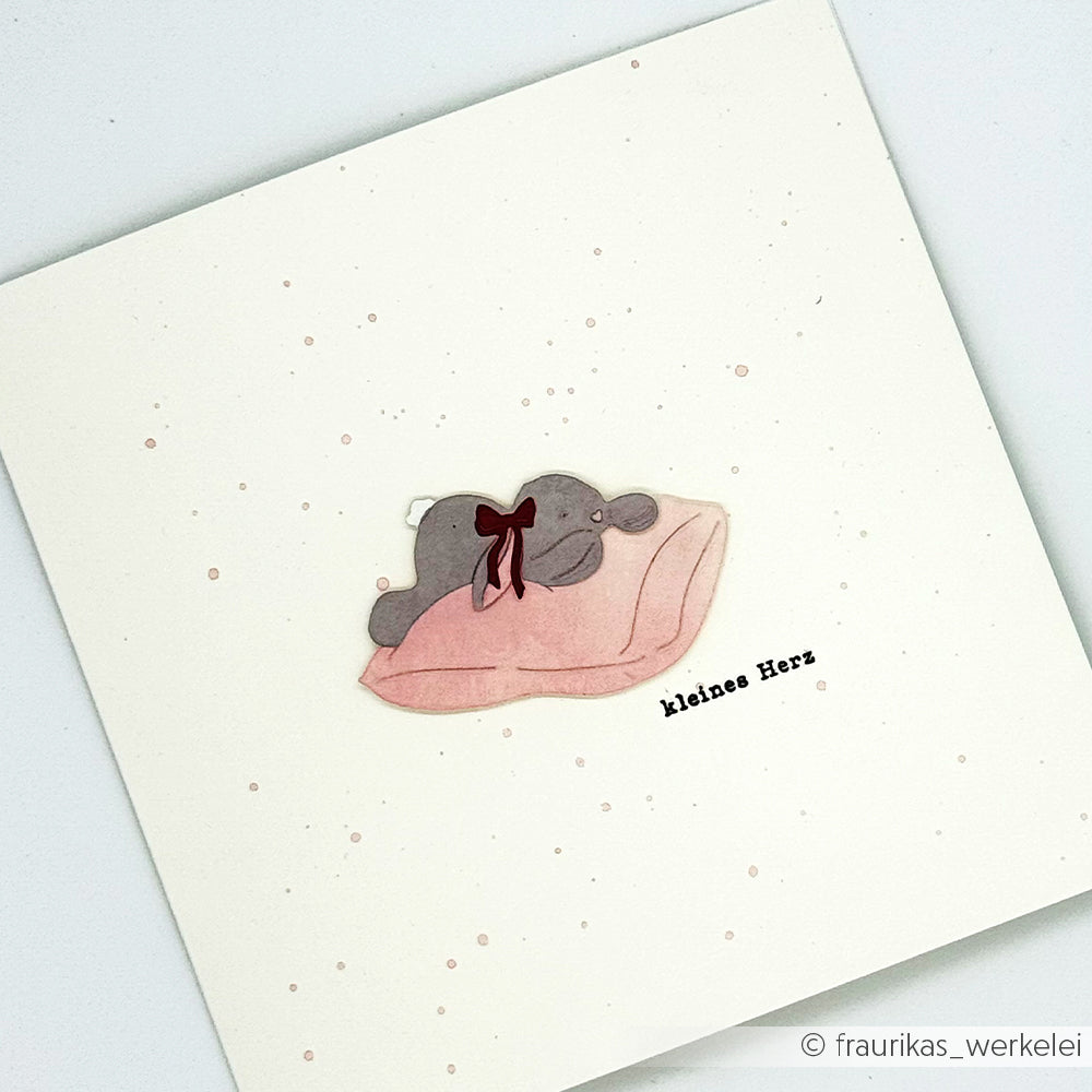 Ein niedliches Elefantenbaby mit roter Schleife liegt auf einer rosa Decke über dem Schriftzug kleines Herz - perfekt für Ihre Alexandra Renke Designpapiere oder in Kombination mit der Motivstanze Müdes Häschen.