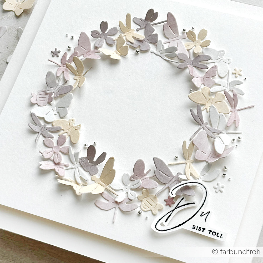 Ein pastellfarbener Papierblumenkranz, hergestellt mit Alexandra Renke Designpapier und Stanzformen, ziert eine weiße Karte mit dem Schriftzug "Du bist toll" unten rechts.