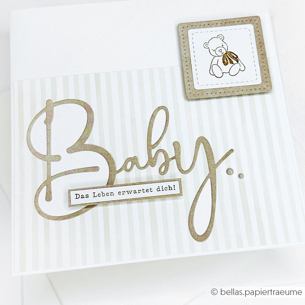 Grußkarte mit "Baby" in großer Schrift unter Verwendung der Alexandra Renke Motivstanze Lebendige Typo Baby, einer Teddybär-Illustration und dem deutschen Text "Das Leben erwartet dich!". Perfekt für Stanzen für Designpapier oder DieCut Systeme.