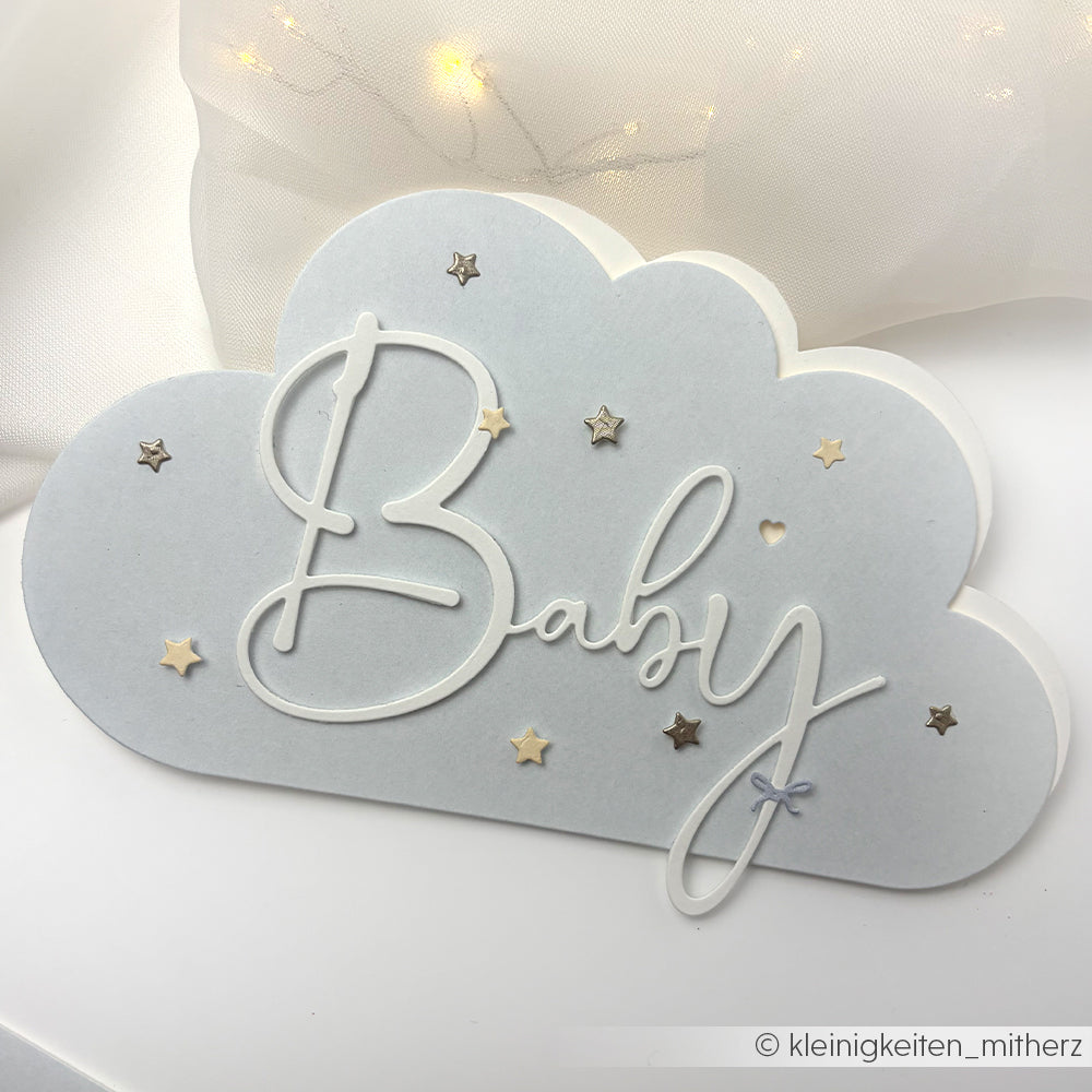 Wolkenförmige Karte, gestaltet mit Alexandra Renke Motivstanze Lebendige Typo Baby in Schreibschrift, verziert mit kleinen goldenen und silbernen Sternen auf weißem Designerpapier.