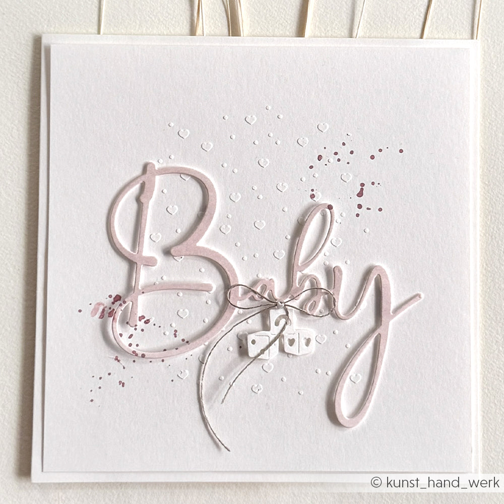 Handgefertigte weiße Karte von Alexandra Renke mit dem Schriftzug "Baby", kleinen silbernen Würfeln und verstreuten Herz- und Punktdekorationen, hergestellt aus hochwertigem Designpapier und gestanzten Systemen für eine einzigartige Note.