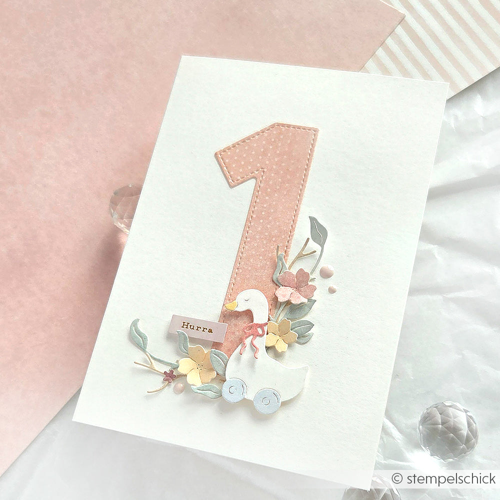 Grußkarte von Alexandra Renke mit einer großen rosa Zahl 1, einer fröhlichen Ente, Blumen und "Hurra" auf hellem Hintergrund.