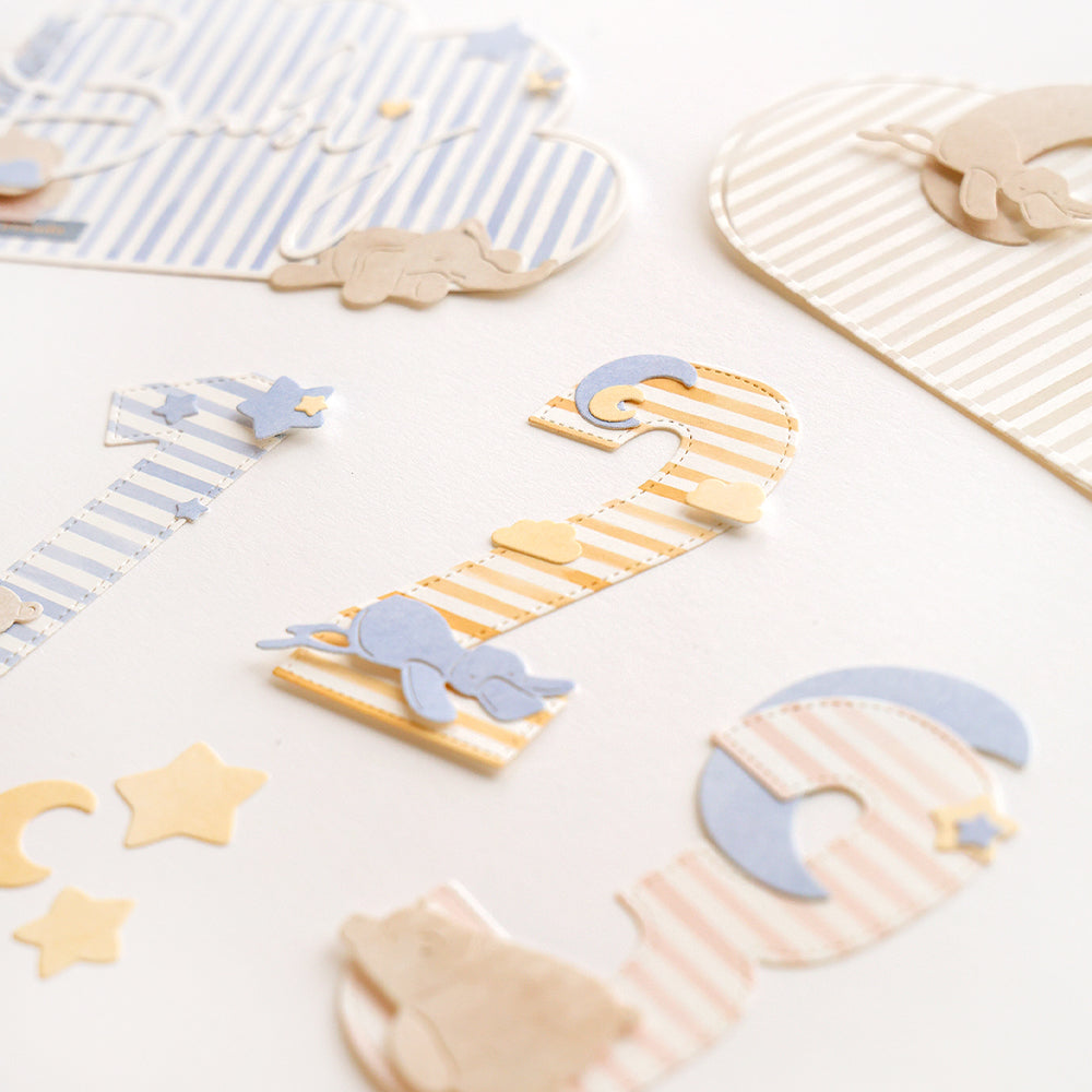 Gestreifte Zahlen- und Formenschnitte aus Alexandra Renke Designpapiere und Motivstanze Zahlen zeigen Tier- und Sternenmotive, die auf weißem Hintergrund angeordnet sind.