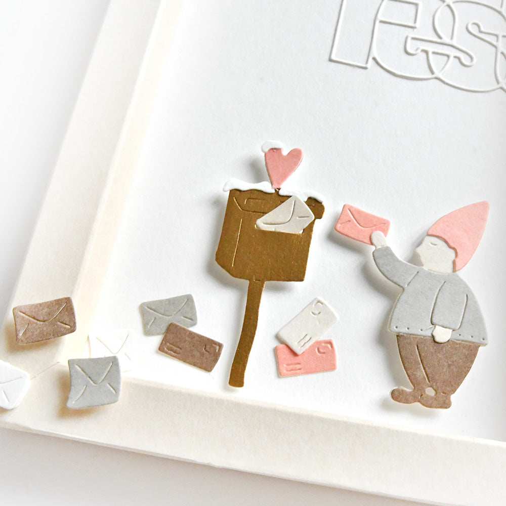 Ein Gnom wirft rosafarbene Post in einen Briefkasten mit Umschlägen, die auf einer weißen Karte verstreut sind. Gestaltet mit der Motivstanze Wichtel-Post von Alexandra Renke und eleganten Designpapieren.