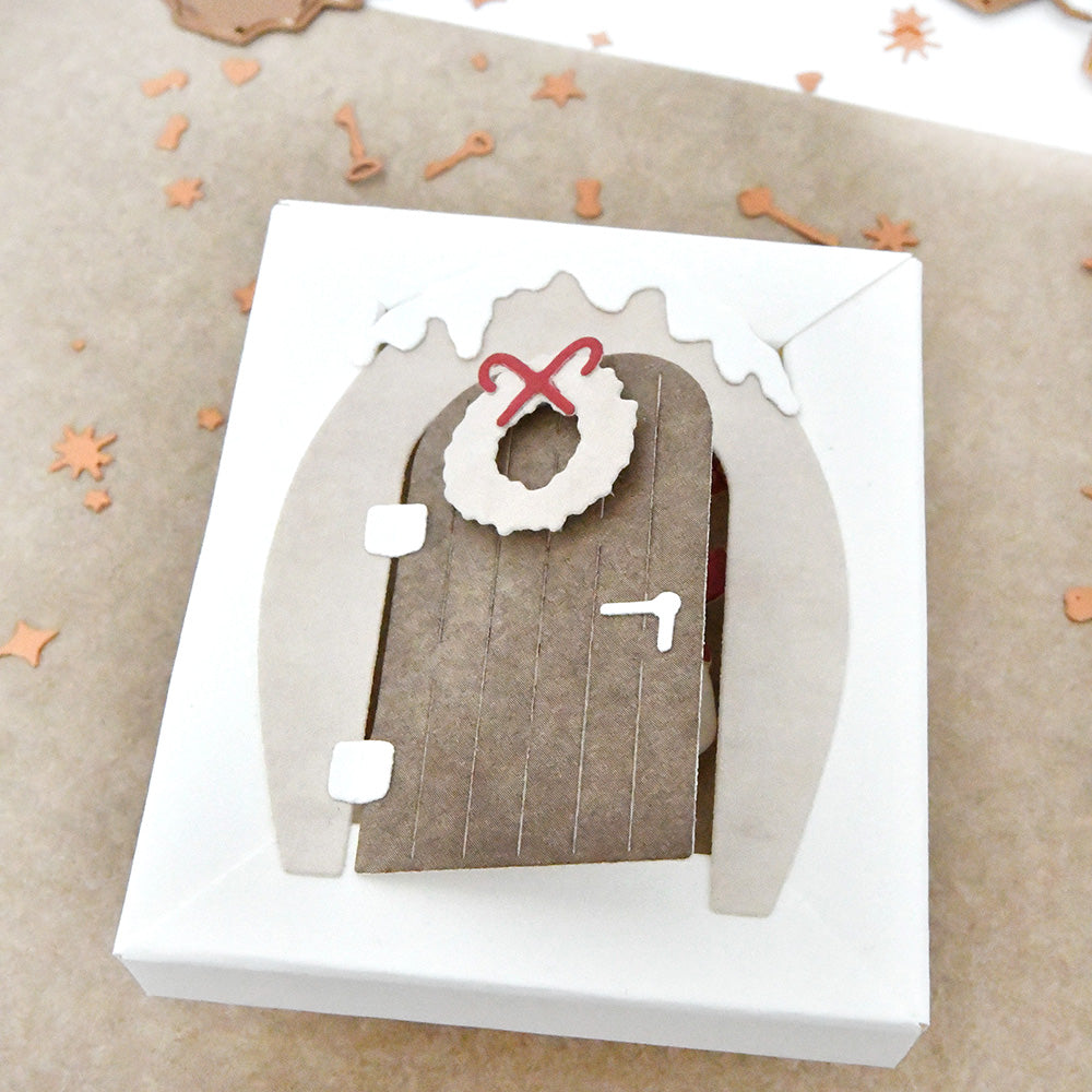 Eine kleine, weiße Schachtel in Form einer Lebkuchentür mit Kranz und Zuckerguss, hergestellt mit der Alexandra Renke Motivstanze Kleine Tür mit Kranz aus hochwertigem Stahl.