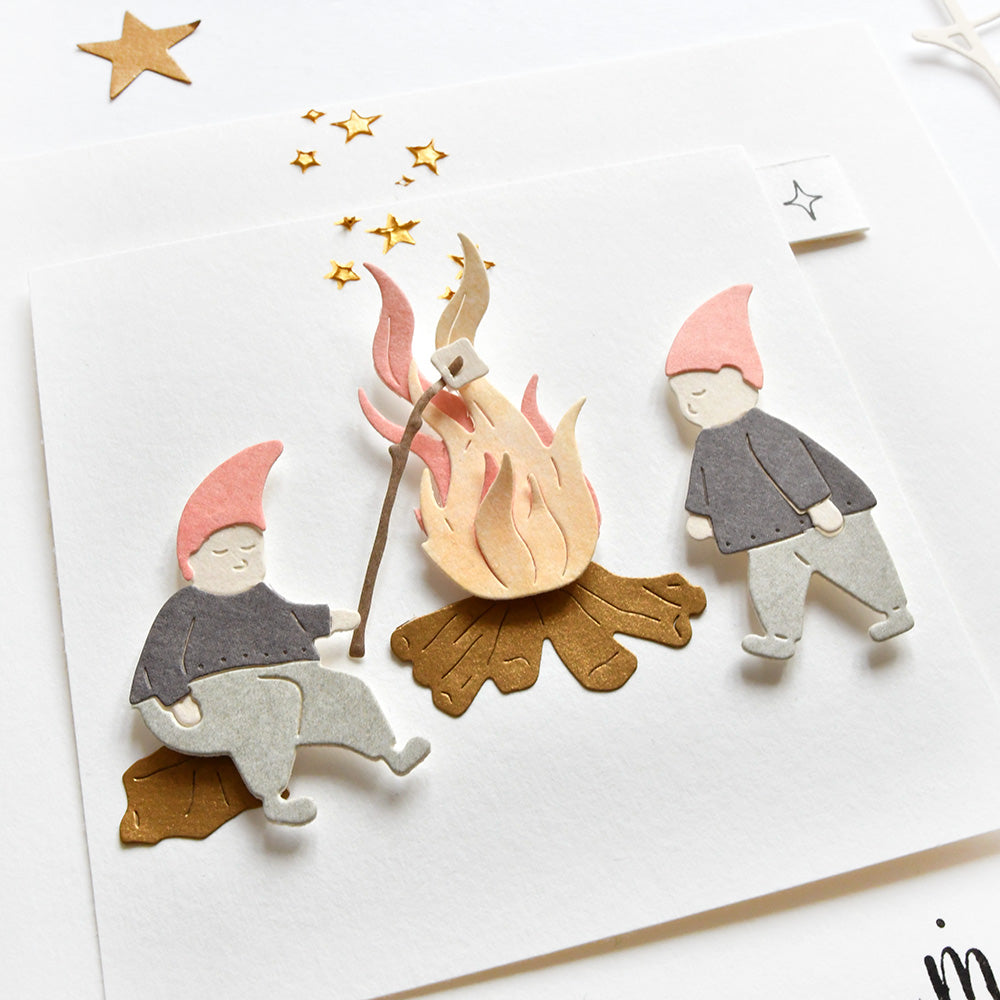 Zwei Papierzwerge mit rosafarbenen Hüten rösten Marshmallows an einem Lagerfeuer unter goldenen Sternen - perfekt von Alexandra Renke zur Verwendung mit DieCut Systemen oder als Akzent für Ihre Designpapiere-Projekte.