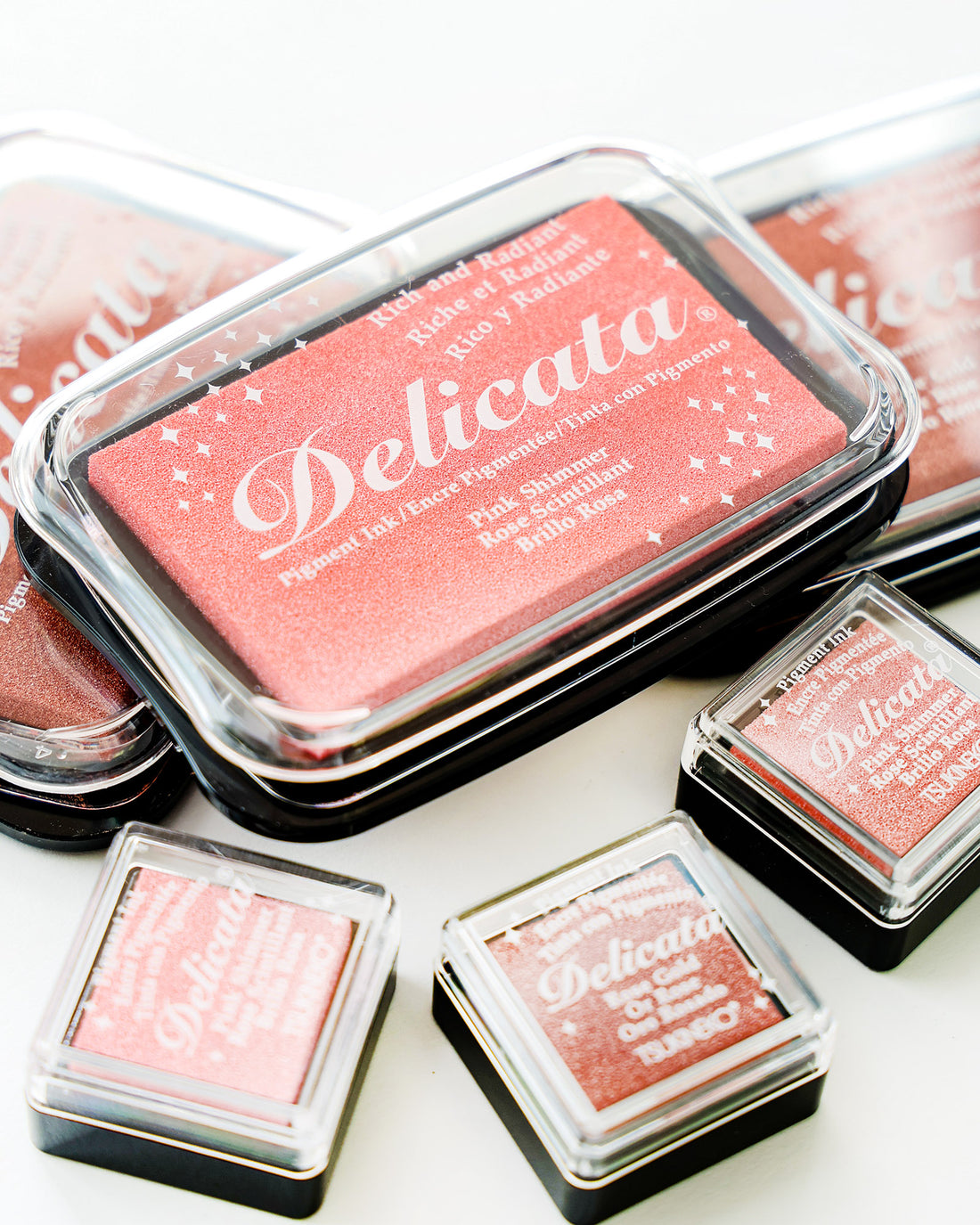 Fünf Delicata-Pigmenttintenkissen in verschiedenen Rosa- und Rottönen sind auf einer weißen Fläche angeordnet.